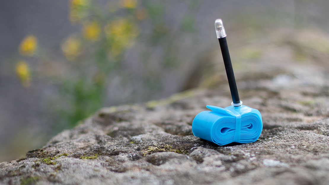 M-Wave TPU inner tube on a rock with a meadow in the background